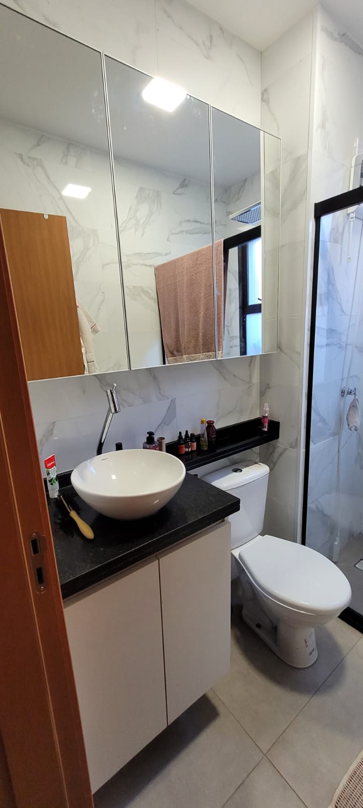 Gabinete branco com cuba redonda e parede de mármore