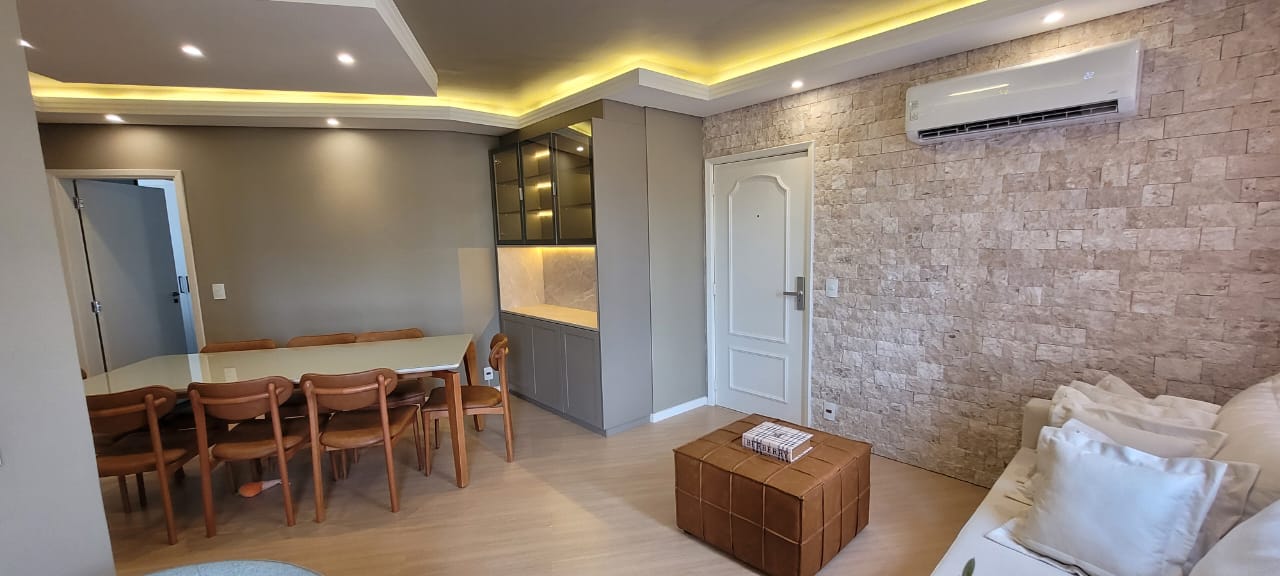 Sala open-plan com cristaleira e parede de pedra